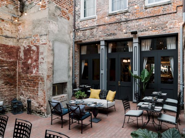 A cozy outdoor seating area with brick walls and cushioned chairs, perfect for dining or relaxing.