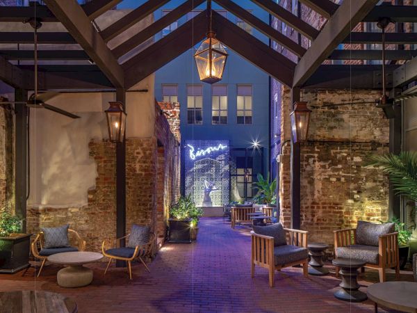 A chic industrial lounge with brick walls, soft lighting, and modern seating; an open ceiling, warm tones, and greenery at dusk, inviting relaxation.