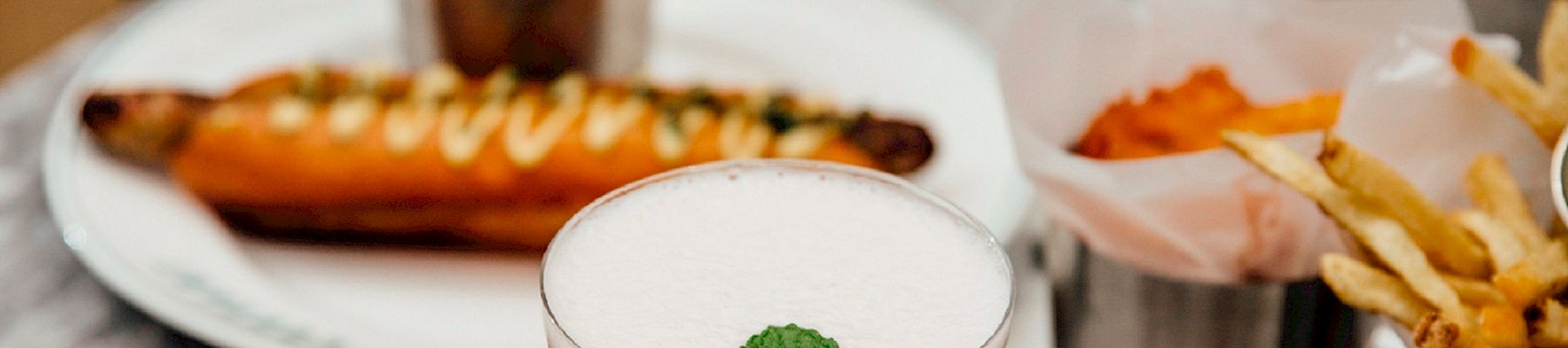 A fancy spread: cocktails, oysters, mussels, fries, olives, prawns, sushi, and a variety of small plates arranged on a marble table.