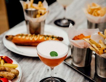 A fancy spread: cocktails, oysters, mussels, fries, olives, prawns, sushi, and a variety of small plates arranged on a marble table.